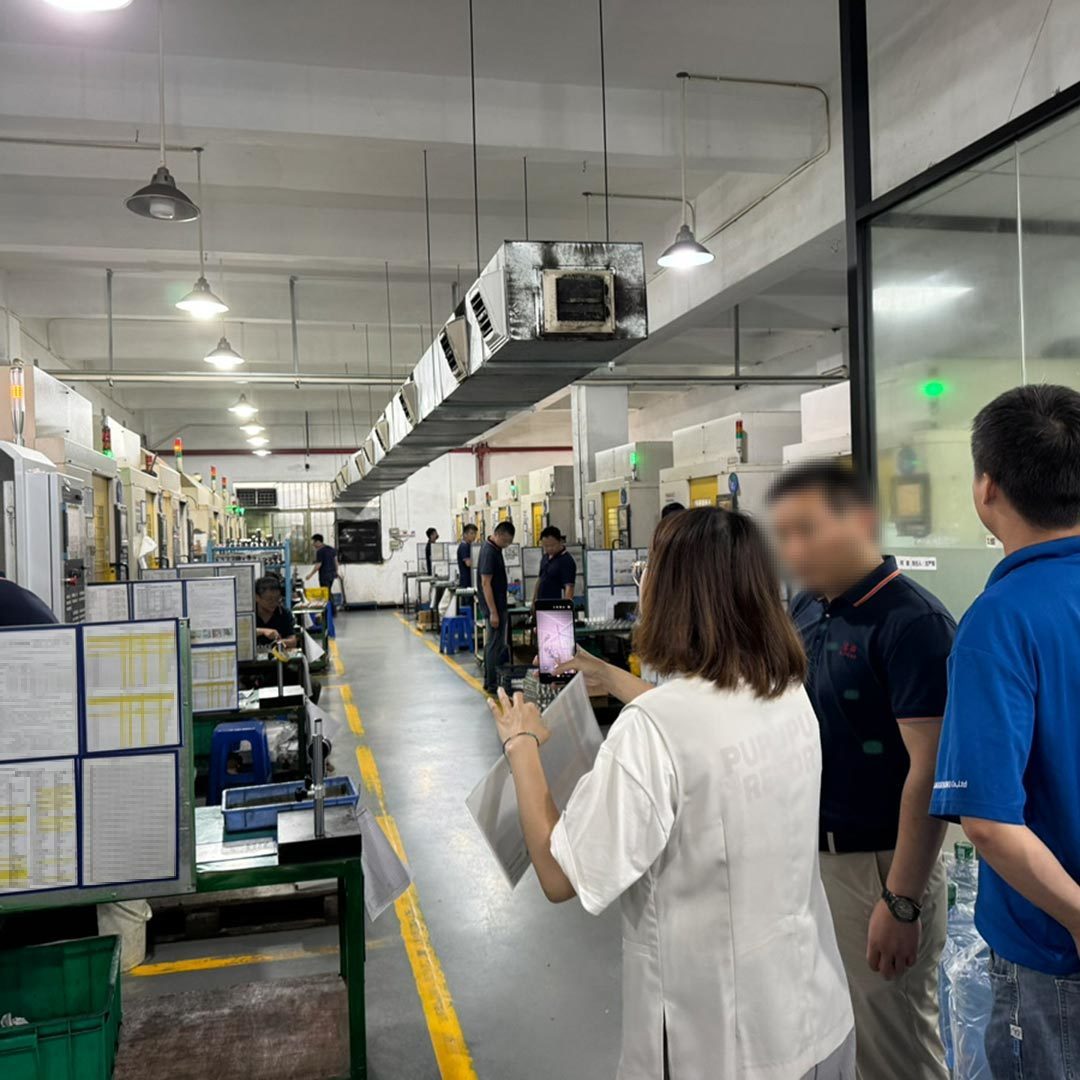 提携工場の視察風景。機械や製品を真剣に見つめる新人品質管理担当者の後ろ姿や、現地スタッフと現場でやり取りしている様子。
